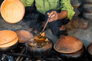 Vieil homme cuisinant de la poitrine de porc braisée vietnamienne et du poisson braisé dans un pot en terre cuite, commune de Hoa Hau, province de Ha Nam, Vietnam près du village de Vu Dai.